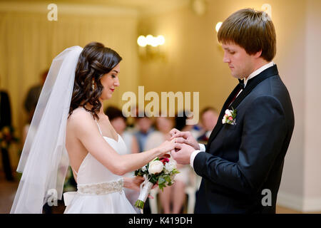 Beauty bride and handsome groom are wearing rings each other Stock Photo