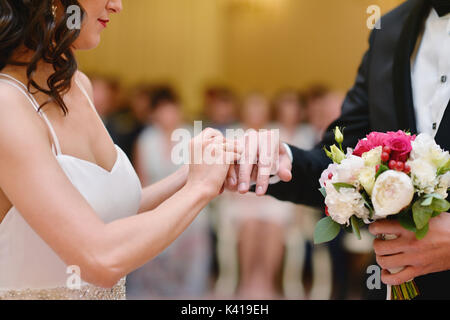 Beauty bride and handsome groom are wearing rings each other Stock Photo