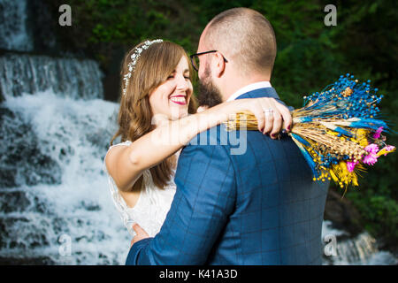 Wedding couple hugging in front of a waterfall Stock Photo