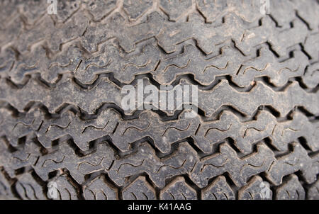 Texture of thick-skinned rubber tire colored in dark gray with carved pattern. Stock Photo