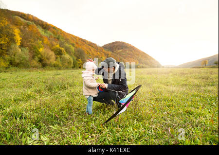 Father with little daughter with kite. Autumn nature. Stock Photo