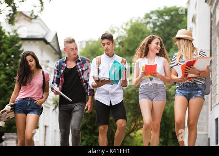 Group of attractive teenage students walking to university. Stock Photo