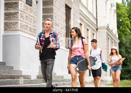 Group of attractive teenage students walking to university. Stock Photo