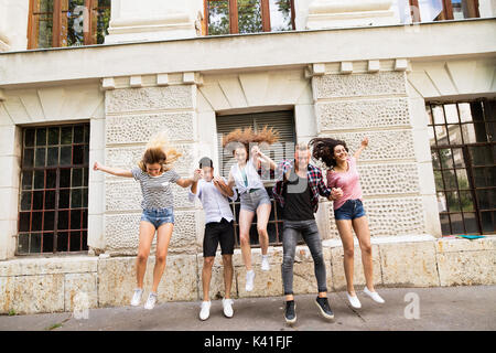 Group of teenage students in front of university jumping high. Stock Photo