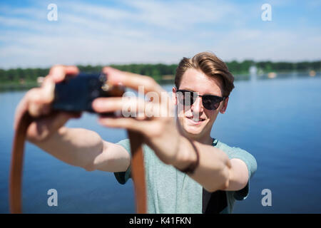 A photo of young, cheerful man taking himself a photo at the lake. Stock Photo