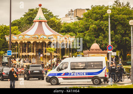 PARIS, FRANCE - May 08, 2017 : police truck is parked in the street next to a carousel and there are policemen on bicycles Stock Photo