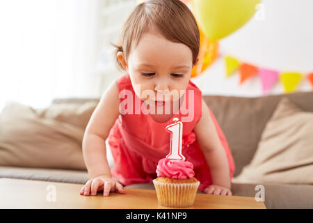 girl blowing to candle on cupcake at birthday Stock Photo