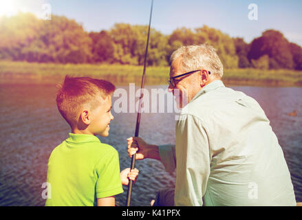 grandfather and grandson fishing on river berth Stock Photo