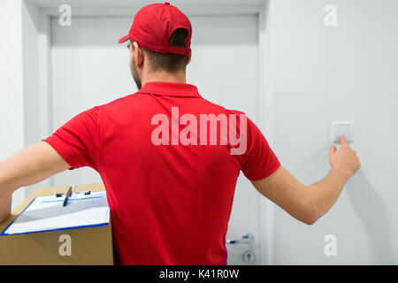 delivery man with parcel box ringing door bell Stock Photo