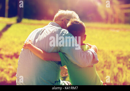 grandfather and grandson hugging outdoors Stock Photo