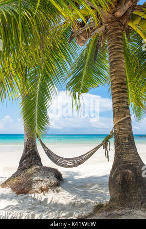Empty hammock between palm trees on tropical beach in Thailand Stock Photo