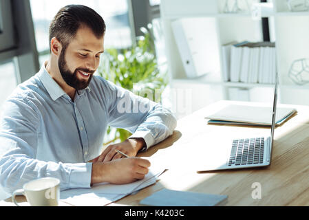 Charming young man making notes in the office Stock Photo