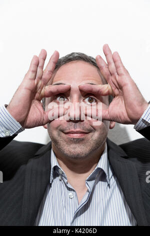 Funny mature man in suit and shirt opened his eyes with fingers smiling joking on white background Stock Photo