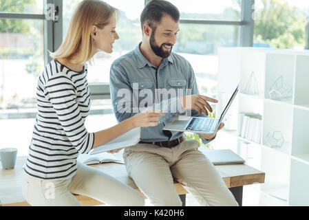 Cheerful colleagues watching a video and discussing it Stock Photo