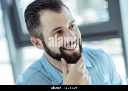 Handsome cheerful man stroking his chin Stock Photo