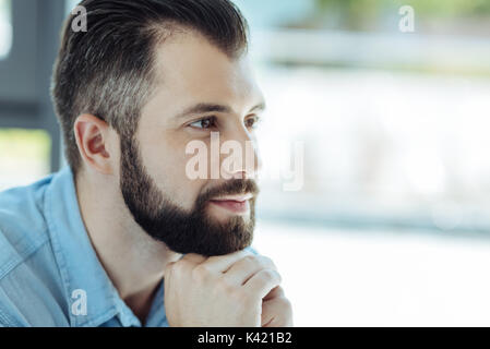 Handsome bearded man resting his chin on folded hands Stock Photo