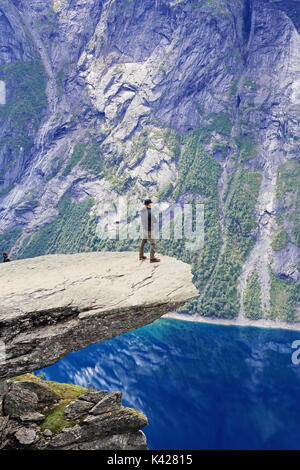 Hiker enjoying view from Trolltunga rock formation in Norway Stock Photo