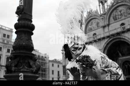 A person in costume at a masquerade during the Carnival of Venice, with large feathers on top of his hat. Stock Photo