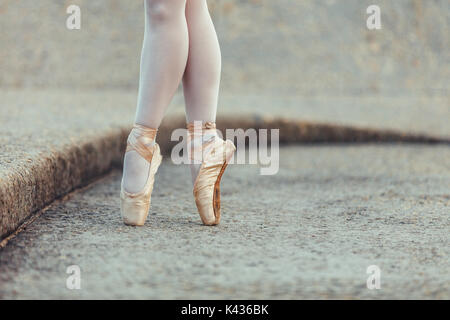 Closeup shot of legs of a female ballet dancer standing on her toes wearing pointe shoes. Ballet dancer practicing dance moves. Stock Photo
