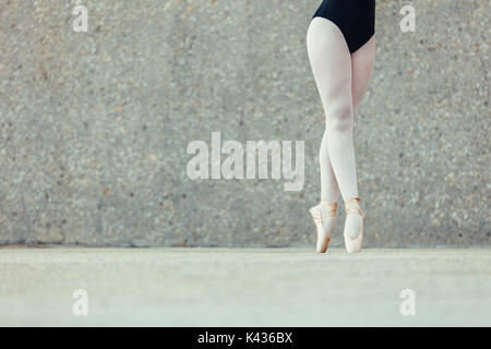 Closeup shot of legs of a female ballet dancer standing on her toes wearing pointe shoes. Ballet dancer practicing dance moves. Stock Photo