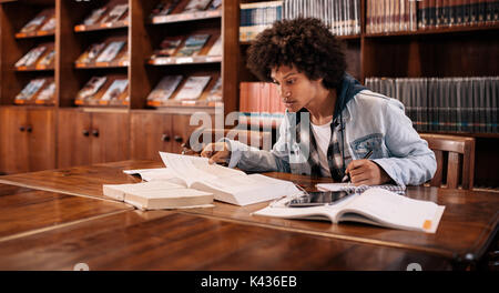 Young afro american student preparing for the exam in the library. college student studying in the library. Stock Photo