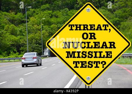Threat, or nuclear missile test? Yellow warning road sign Stock Photo