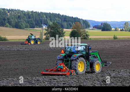 SALO, FINLAND - AUGUST 20, 2017: Farmers cultivate field with two John Deere tractors and Kverneland harrows on a beautiful day of early autumn. Stock Photo