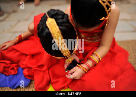 Kathmandu, Nepal. 04th Sep, 2017. Young girls impersonate as a Kumari or living Goddess playing mobile phones during celebration of Kumari puja at Basantapur Durbar Square, Katmandu, Nepal on Monday, September 04, 2017. Altogether 108 young girls under the age of nine gathered for the Kumari puja, a tradition of worshiping, which believes doing puja save small girls from diseases and bad luck in future. Credit: Narayan Maharjan/Pacific Press/Alamy Live News Stock Photo
