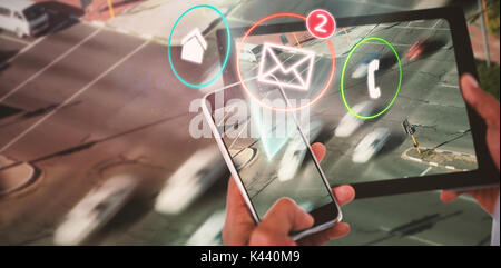 Close up of hands using digital tablet and mobile phone against blurred motion of vehicles on road Stock Photo