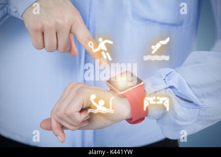 Midsection of businesswoman pointing at smart watch against purple vignette Stock Photo