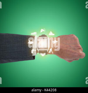 Cropped hand of businessman wearing smart watch against green vignette Stock Photo