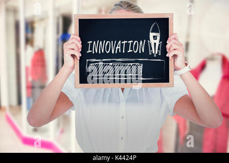 Woman with face covered by chalkboard against blurry front shop Stock Photo