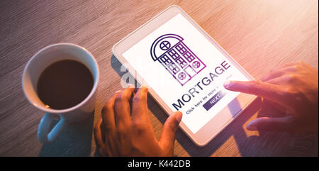 Composite image of mortgage text with icon against cropped hands of buisnessman using digital tablet at desk Stock Photo