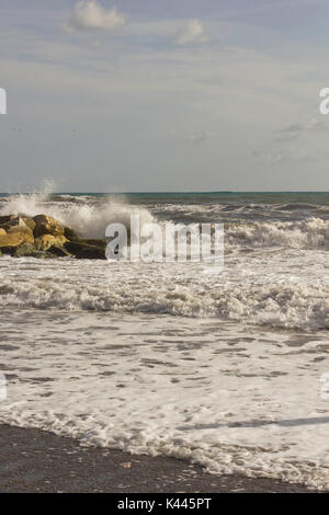 MARINA DI MASSA, ITALY - AUGUST 17 2015: Wave smash into the rocks in a sunny day with rough seas in Tuscany Stock Photo