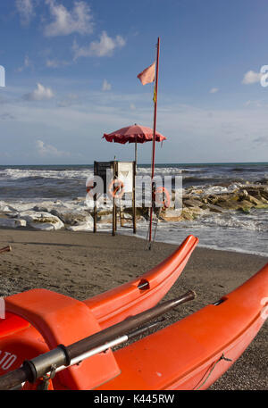 MARINA DI MASSA, ITALY - AUGUST 17 2015: Lifeguard tower and rowing boat on the shoreline with rough seas, nobody around Stock Photo