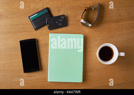 A note with Smart key, card wallet, smart watch, smart phone and a cup of coffee on a wooden table. Stock Photo