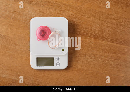 white food scales with pink tapeline on a wooden table Stock Photo