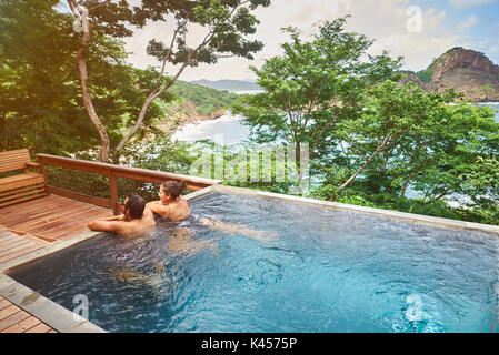 Hispanic couple staying in spa pool on sunny nature background Stock Photo