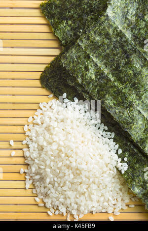 Green nori sheet and sushi rice on bamboo mat. Top view. Stock Photo