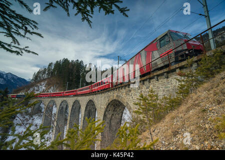 Filisur, Switzerland. The red train running away on the viaduct. Stock Photo