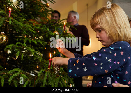 Toddler decorating Christmas tree on Christmas Eve Stock Photo