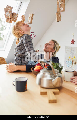 Mother and little daughter with advent calendar, sitting at kitchen table, Stock Photo