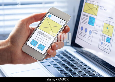 Mobile responsive website development with UI/UX front end designer previewing wireframe sketch layout design mockup on smartphone screen Stock Photo