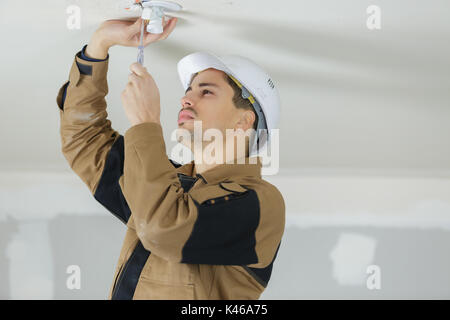 electrician fitting a ceiling light Stock Photo