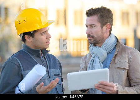 engineer with hard hat using tablet talking to supervisor Stock Photo
