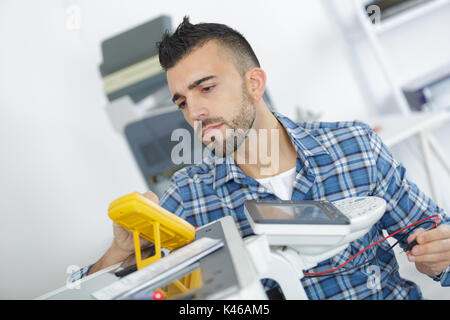 high angle view of technician checking machine with digital multimeter Stock Photo