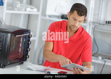 man repairing domestic oven in kitchen Stock Photo