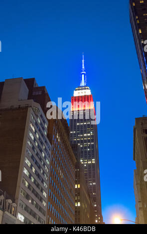 Empire State Building at night showing the colors of the American flag, red, white and blue