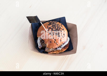 Hamburger on wooden table, one bite taken out of it. Stock Photo