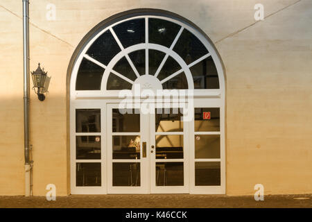 New large round arch door with rungs in a yellow plastered house wall. Stock Photo